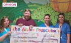 Andrew Batchelor with nurses at the Tayside Children's Hospital. They are standing in front of a colourful mural and holding a large cheque made out to the Archie Foundation for £1,700.