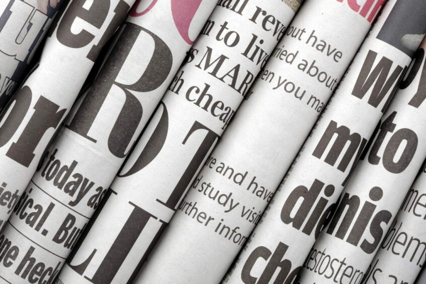 Close up of newspapers headlines, in a stack of folded papers.