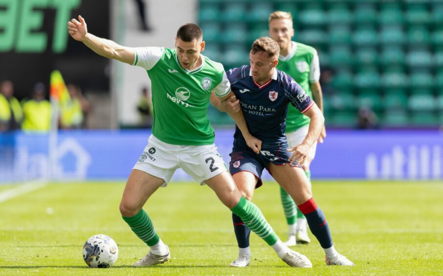 Raith's Lewis Vaughan grabs the arm of Hibs defender Lewis Miller as the pair challenge for the ball.