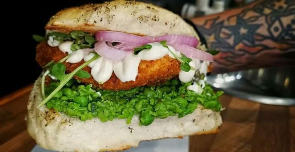 A fish burger with mushy peas, lettuce, pickled onions and mayo.