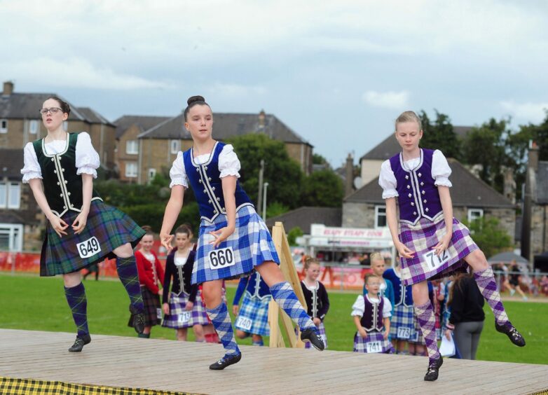 Trio of Highland dancers performing on stage at the Games. 