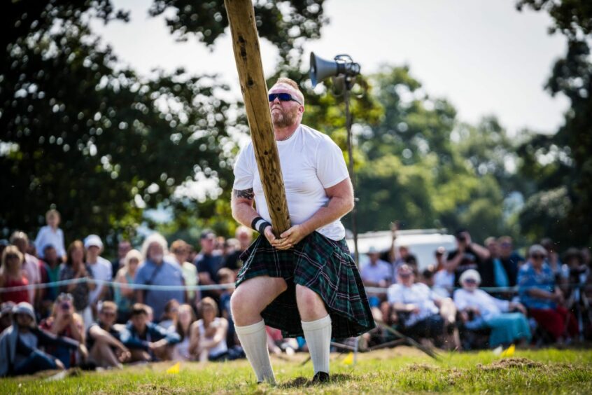 Large man tossing caber at Perth Highland Games in 2022.