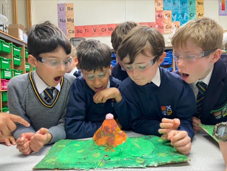 Primary pupils at the High School of Dundee marvel over a model volcano they have created.