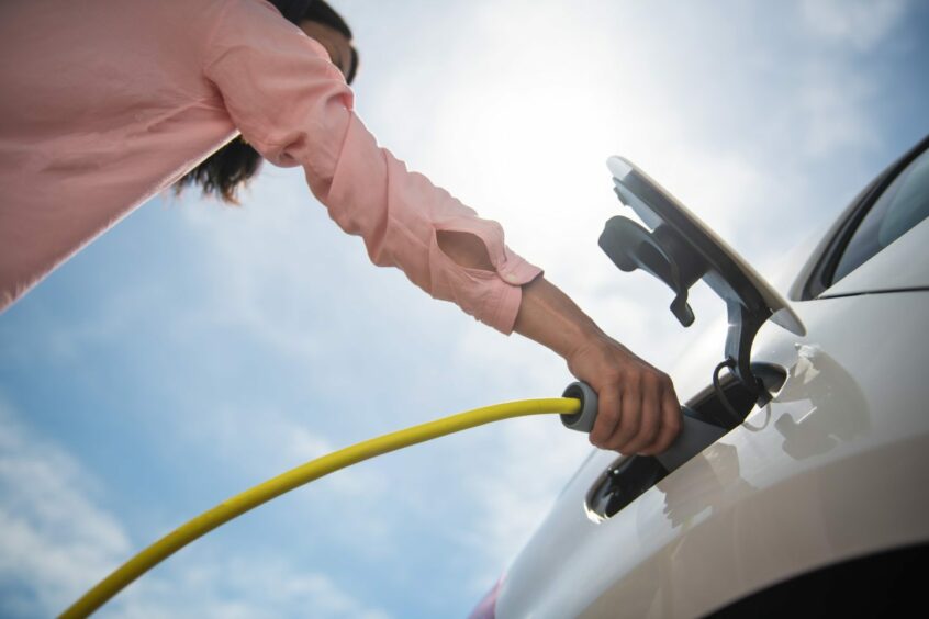 a worm's eye view of a woman charging an electric vehicle