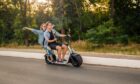 Happy young couple driving electric bike during summer
