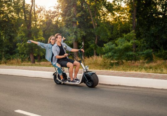 Happy young couple driving electric bike during summer