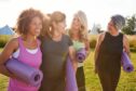 group of female friends walking outdoors carrying yoga mats