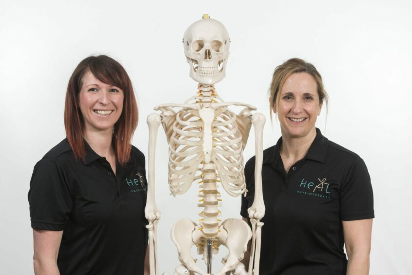 two women from Heal Physiotherapy pose beside a skeleton. Heal is among several local businesses providing hair and body care for its clients 