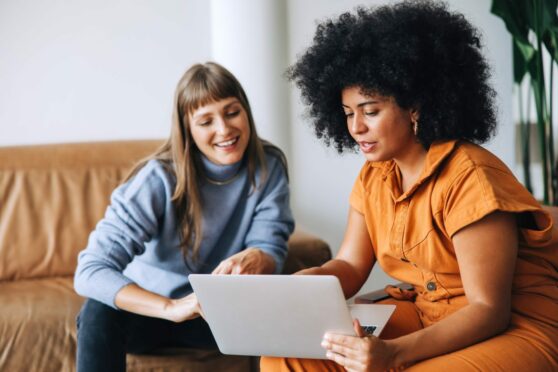 two women huddle over a laptop