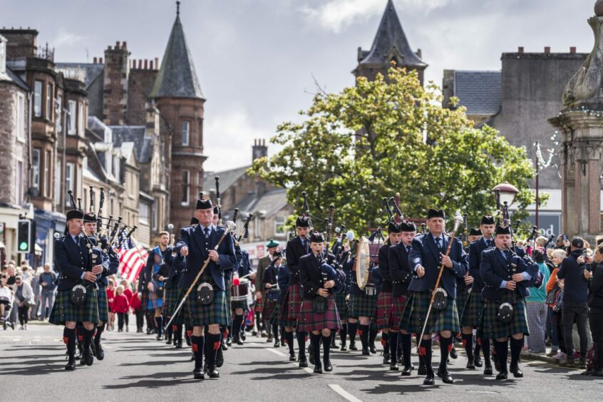 Pipe band marching through centre of Crieff in the summer