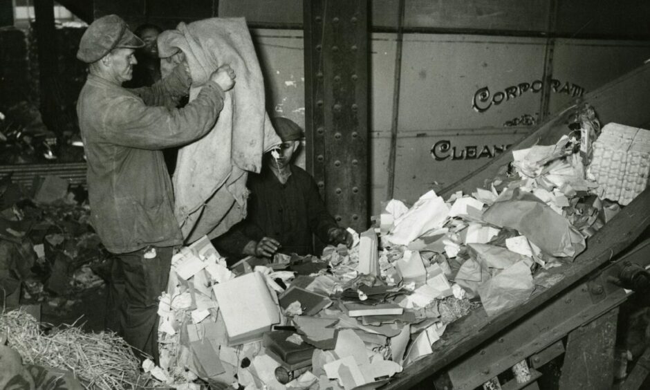 A staff member emptying bags of waste paper on to a conveyor belt at Dundee Salvage Depot in 1948. Image: DC Thomson.