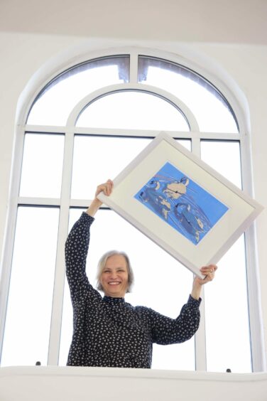 Babs Pease holding up one of her paintings.