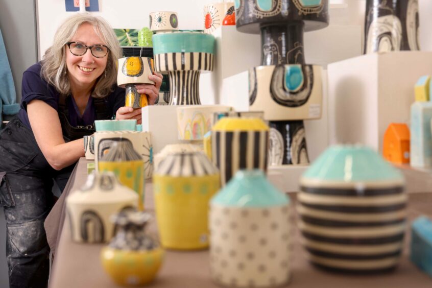 Ceramicist Ceri White with colourful pots in her studio.