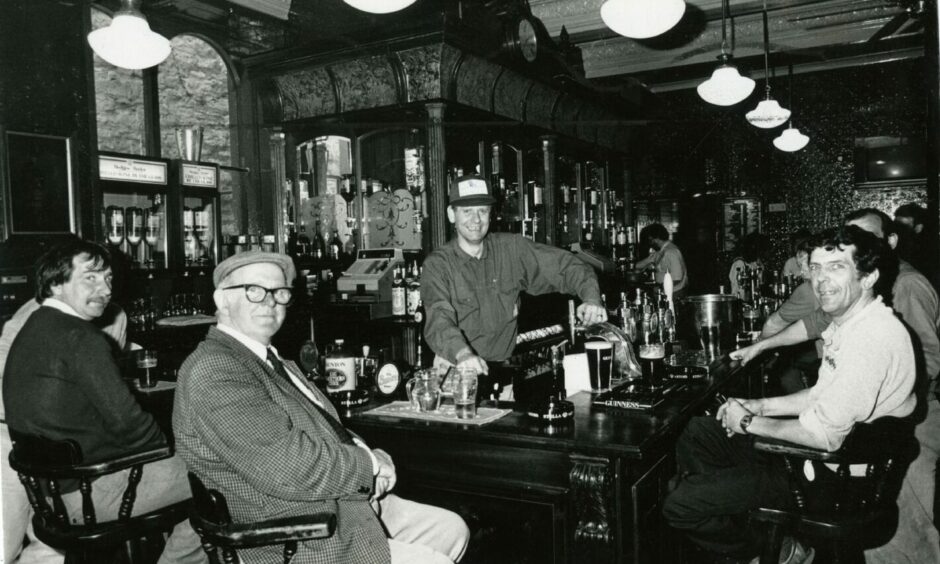 Mine host Allan Bannerman alongside his customers in the Phoenix Bar in July 1987. Image: DC Thomson.