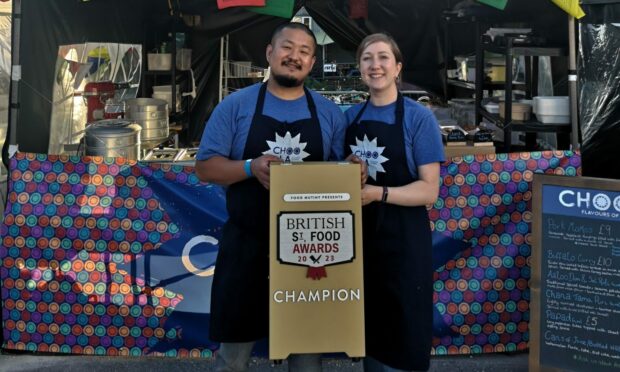 Ameer and Nicole Limbu in front of the Choola food stall holding a British Street Food Awards Champion sign.