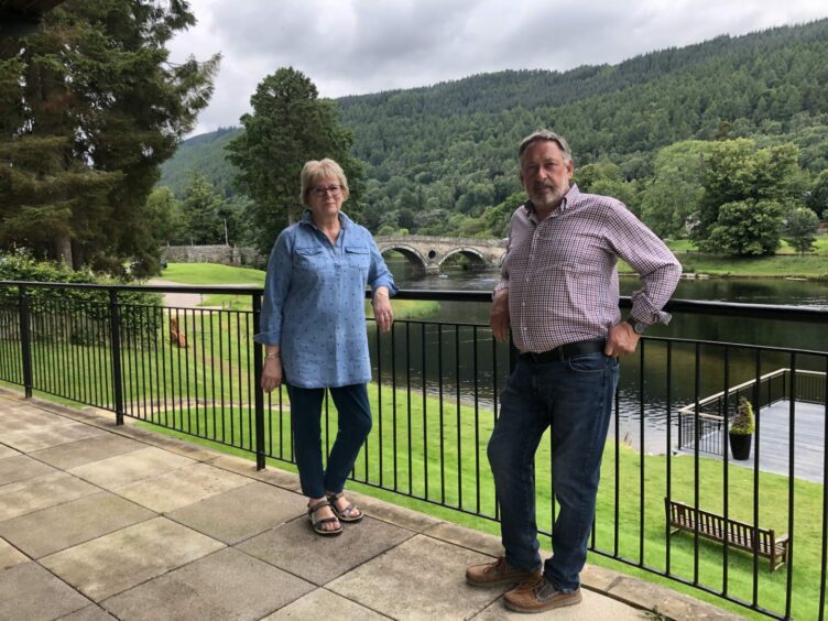 Shirley Shearer and Colin Morton of Kenmore and District Community Council leaning against railings next to the River Tay in Kenmore.