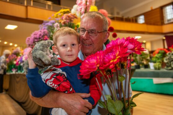 Austin Lindsay, 3, from Monikie admires his grandad Gordon Robbie's water lily dahlias which took a first prize. Image: Kim Cessford/DC Thomson