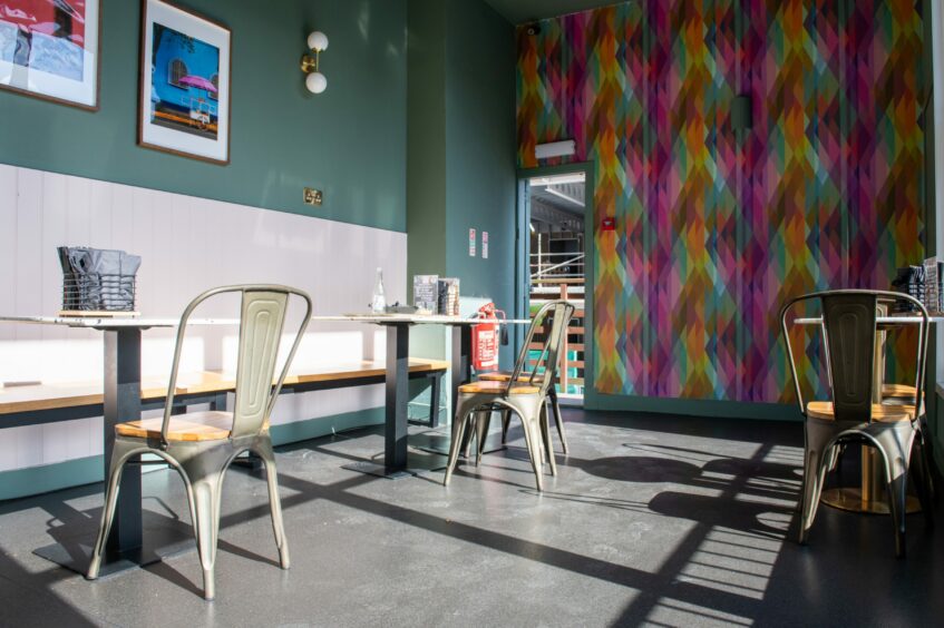 Inside Wee Mexico, with a blue-green wall and a funky colourful wallpaper on the back wall.