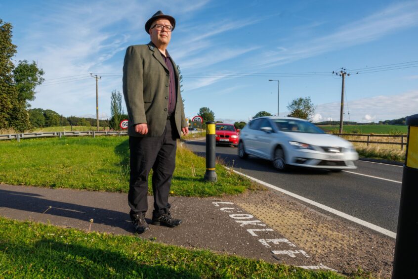 Councillor Jonny Tepp stands on the roadside near the dangerous A92 crossing. 