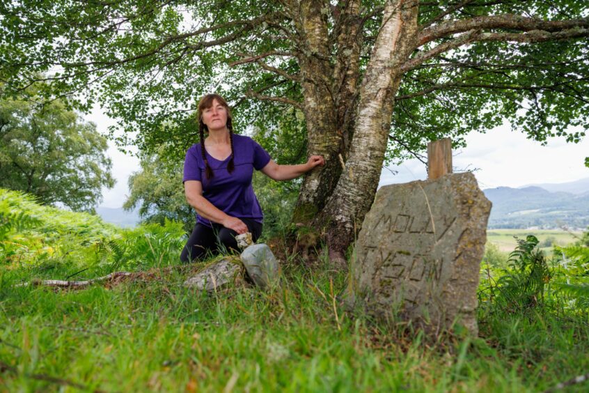 Alexa Reid kneeling next to a grave stone in the old pet cemetery at Auchingarrich Wildlife Park.