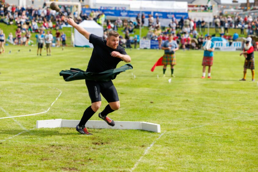 Kilted heavyweight athlete throwing the hammer at Crieff .