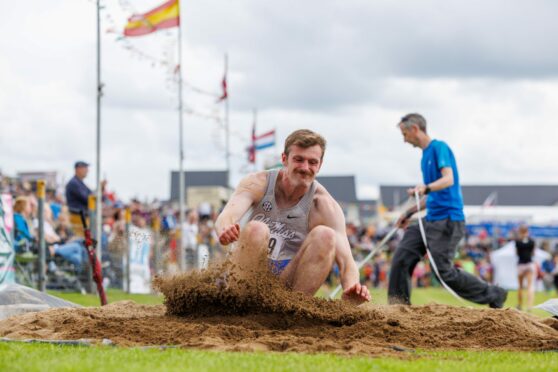 long jumper kicking u; sand as he lands at Crieff Highland Gathering.