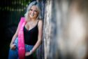 Mackenzie Connor with pink sash leaning against a tree.