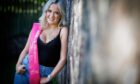 Mackenzie Connor with pink sash leaning against a tree.