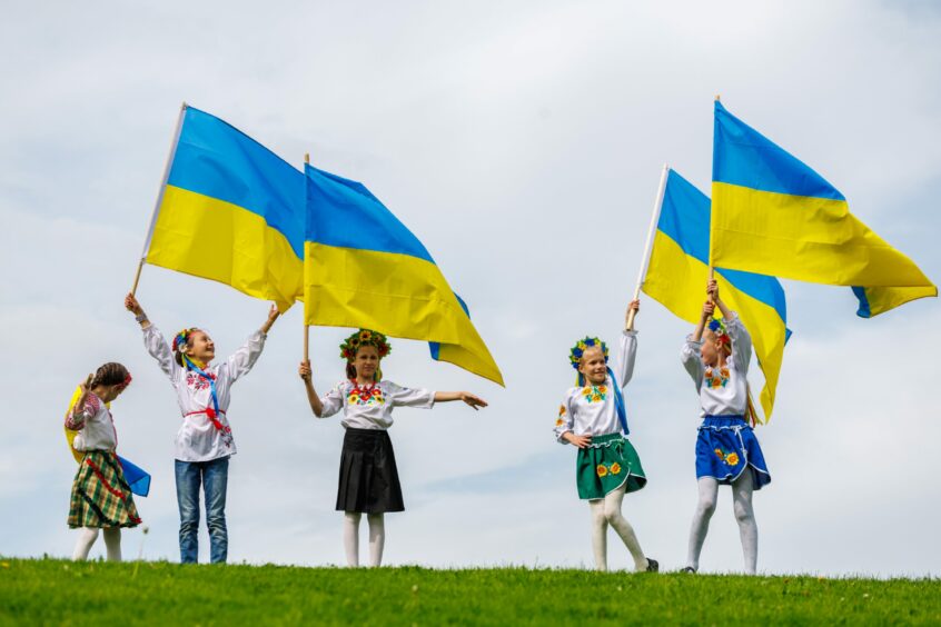 five small children with Ukrainian flags and national dress.