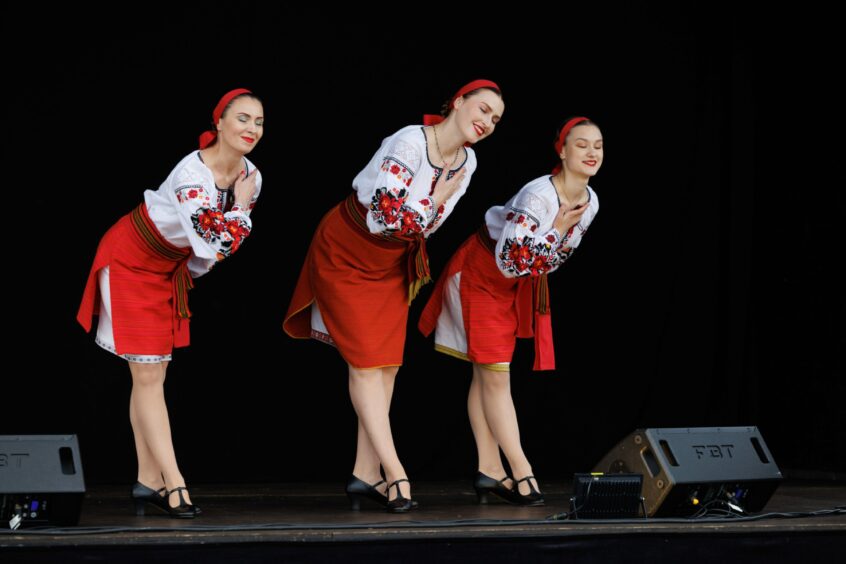 Three women in the band Oberish in Ukraine national dress bow with hands on hearts.