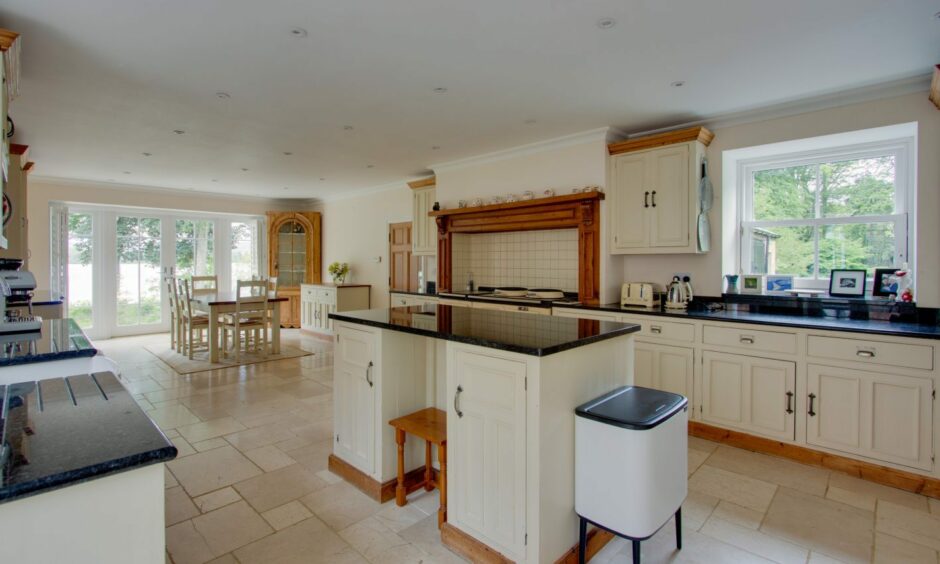 The kitchen and dining area of Lintrathen House, with cream cupboards, black countertops and wooden accents