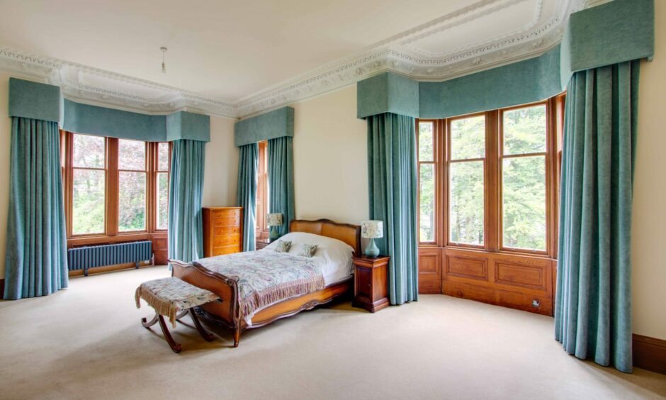 A bedroom in Lintrathen House with the large windows letting in light.