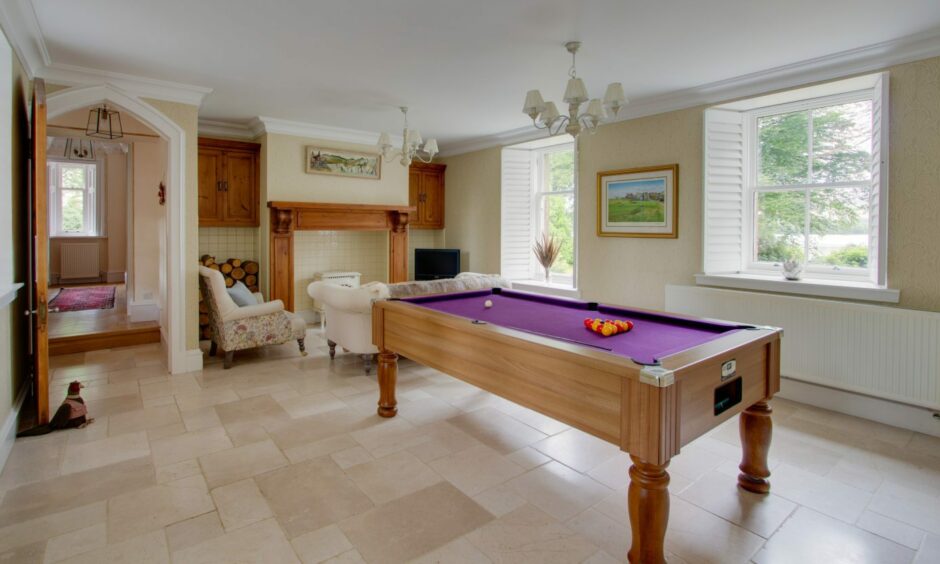 The games room in the property, featuring a fireplace, a sofa and armchairs and a pool table