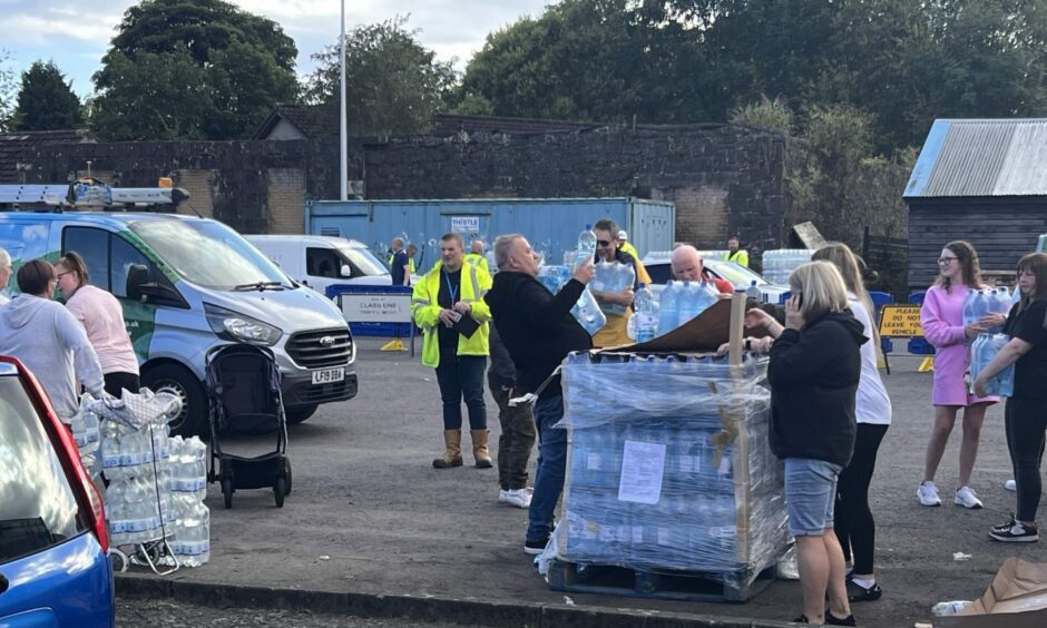 Scottish Water staff hand out bottled water.