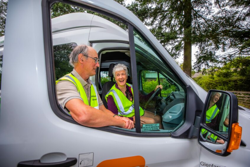 Robert and Christine Morton laughing next to open door of Glenfarg community transport minibus