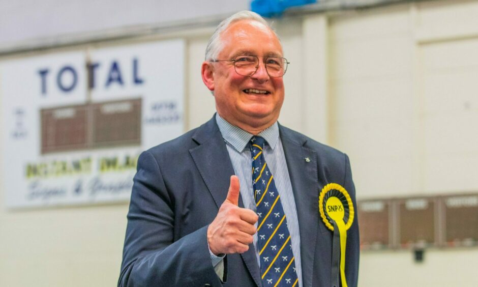 Councillor Andrew Parrott wearing a SNP rosette giving a thumbs up sign