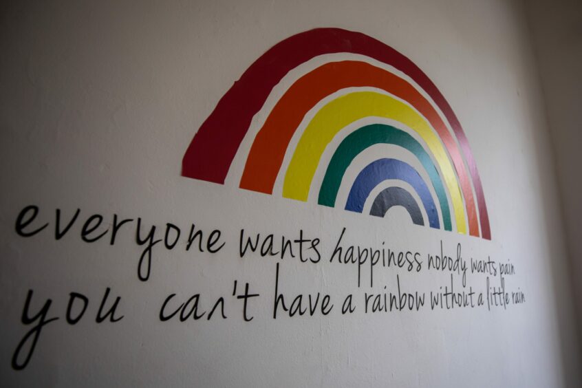 mural with rainbow and the words 'Everyone wants happiness, nobody wants pain. You can't have a rainbow without a little rain' at Moore House Dunkeld. 