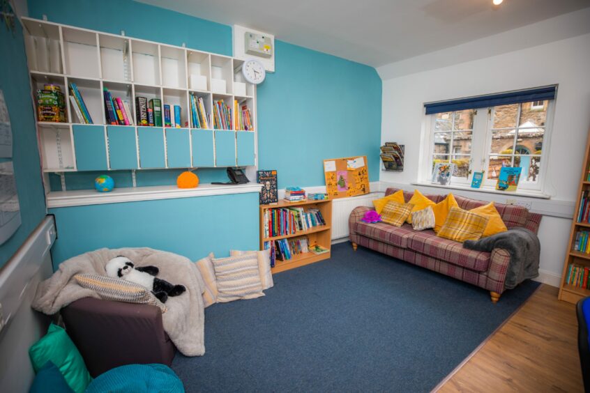 Classroom area with books, sofa, soft toys and calming blue walls and carpets.