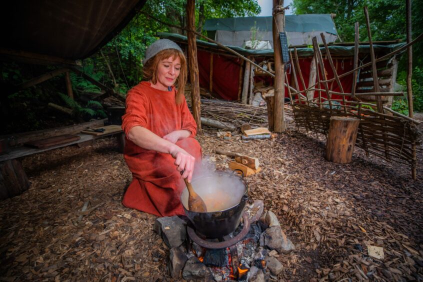 Jenny Robertson, in Iron Age clothing, cooking up a stew on an open fire at the Scottish Crannog Centre.