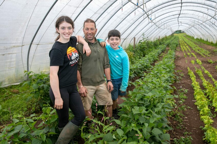 12-year-old Erin, Derek and 10-year-old Calum inside the Bellfield Organic Nursery polytunnel.