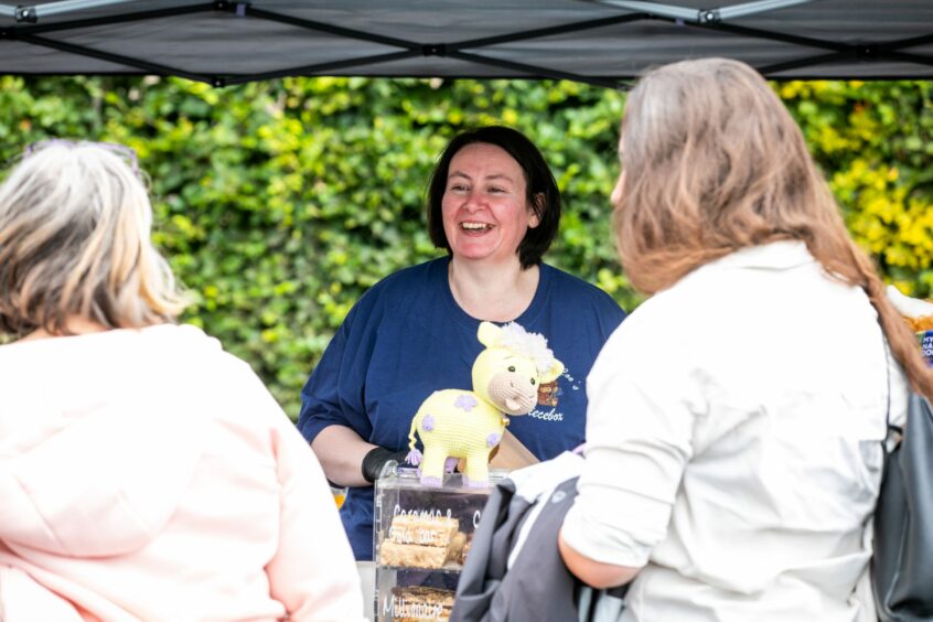 Lady smiling as she talks to customers at Hairy Coo deli stand at the Barrie Box summer fair.
