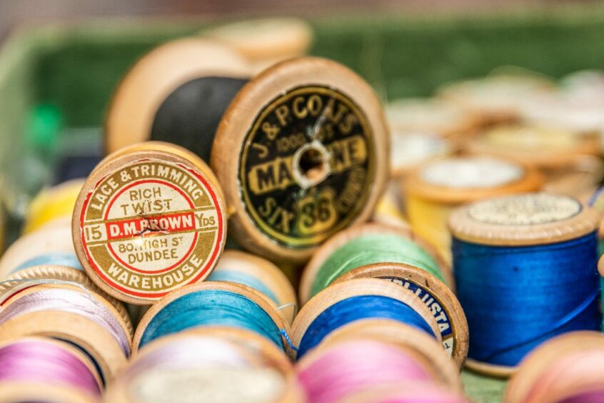 Image shows a close up shot of wooden spools of thread.