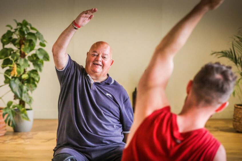 Martin follows Finlay's lead at the chair yoga class in Dundee.