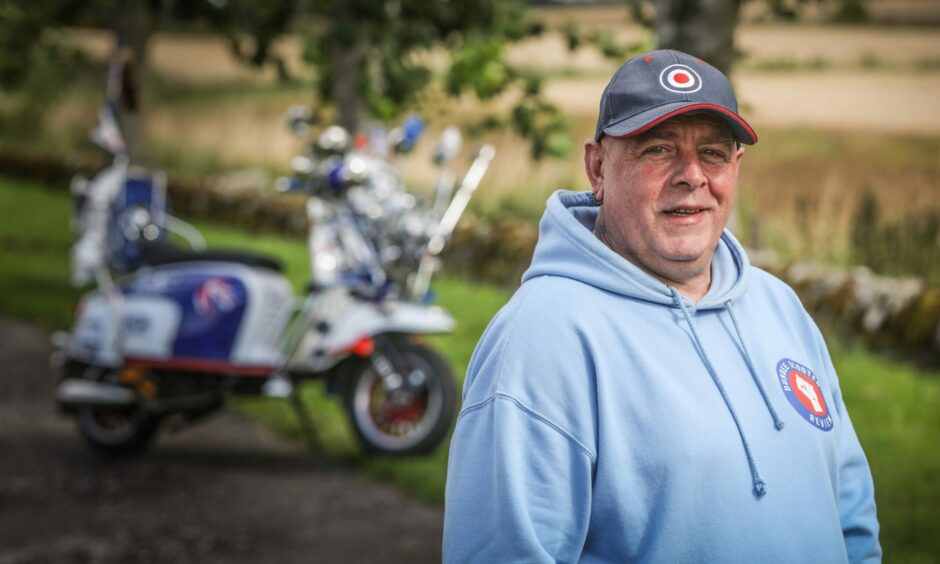 Carl Garner, 51, with the scooter which saved his life after a crash. Tests revealed he had bladder cancer.