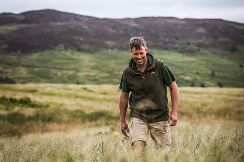 Perthshire farmer Alex Brewster walks through the long grasses on his farm. 