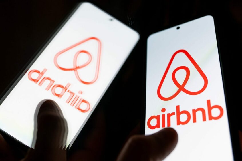 Person holding phone with Airbnb app open
