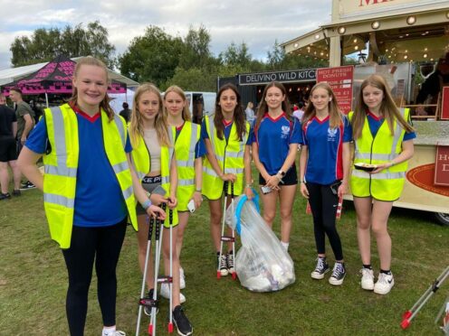 Seven members of Perth City Swim Club with litter picking gear at Crieff Highland Gathering.