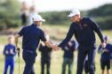 Connor Graham of Great Britain and Ireland is congratulated by Calum Scott after holing a birdie putt on the fourth green on the Old Course. Image: Shutterstock.