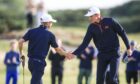 Connor Graham of Great Britain and Ireland is congratulated by Calum Scott after holing a birdie putt on the fourth green on the Old Course. Image: Shutterstock.