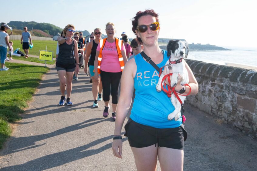 A woman holding a small dog during the parkrun
